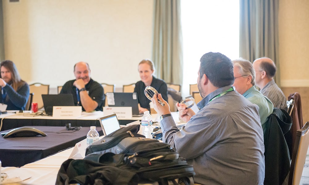 people holding machine parts sitting in a conference room